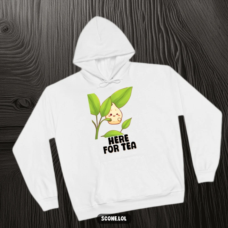 Funny Hoodie: A scone character grins happily while hiding behind a large tea leaf, offering a cozy and humorous vibe.
