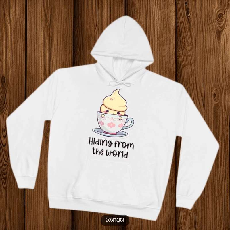 Funny hoodie with a charming scone character peeking merrily from behind a stylized teacup graphic, radiating warmth.